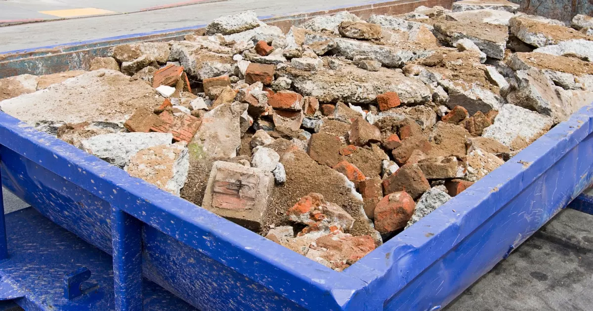 Large blue dumpster filled with bricks and concrete from construction debris removal